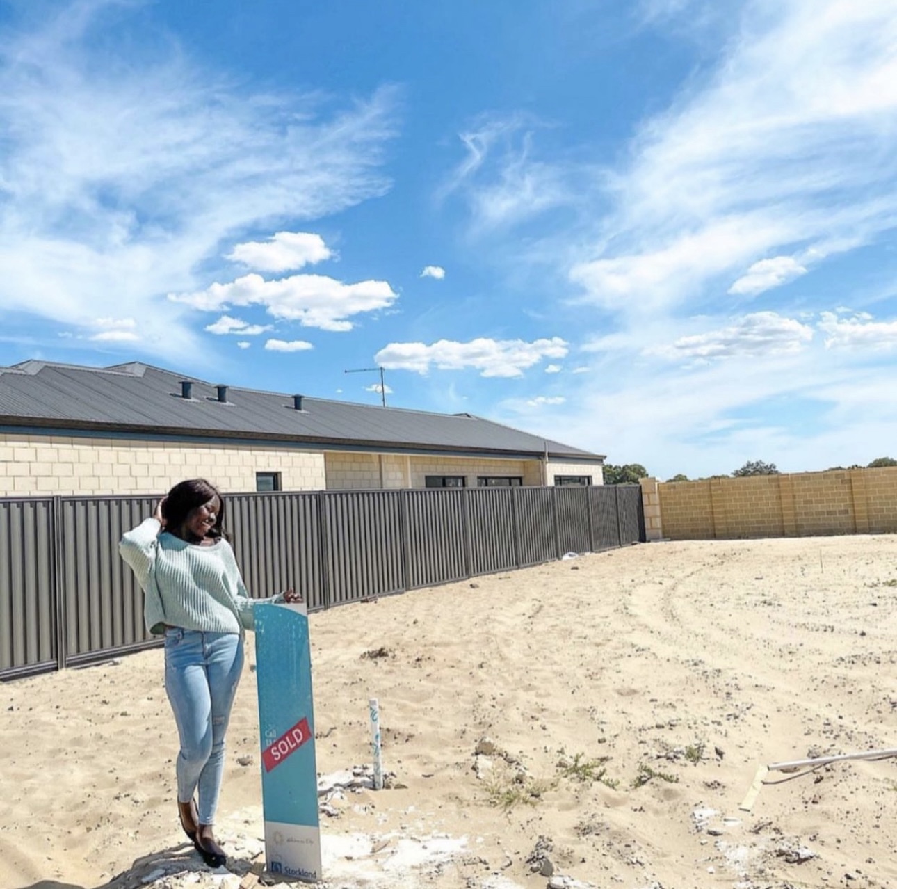 Client celebrating with sold sign on building site